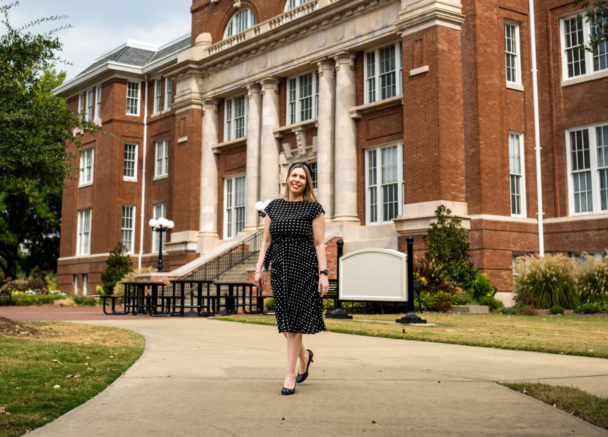 Dr. Lourdes Cardozo-Gaibisso stands in front of Lee Hall in a casual pose.